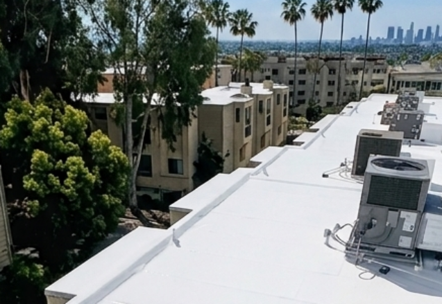 White commercial flat roof restored with silicone coating near Long Beach skyline
