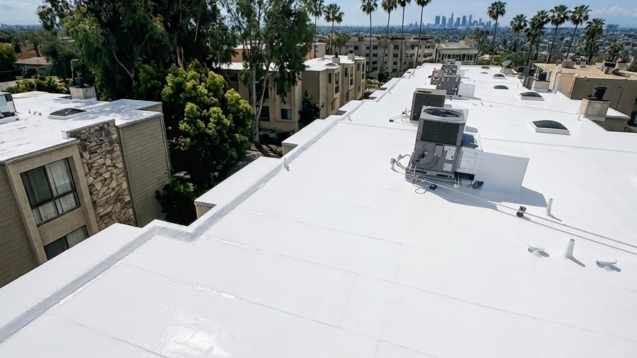 Clean white commercial roof restoration with rooftop HVAC and Southern California skyline