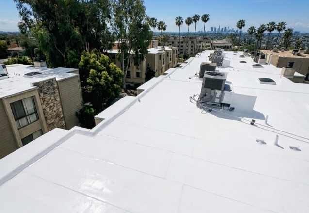 Clean white commercial roof restoration with rooftop HVAC and Southern California skyline