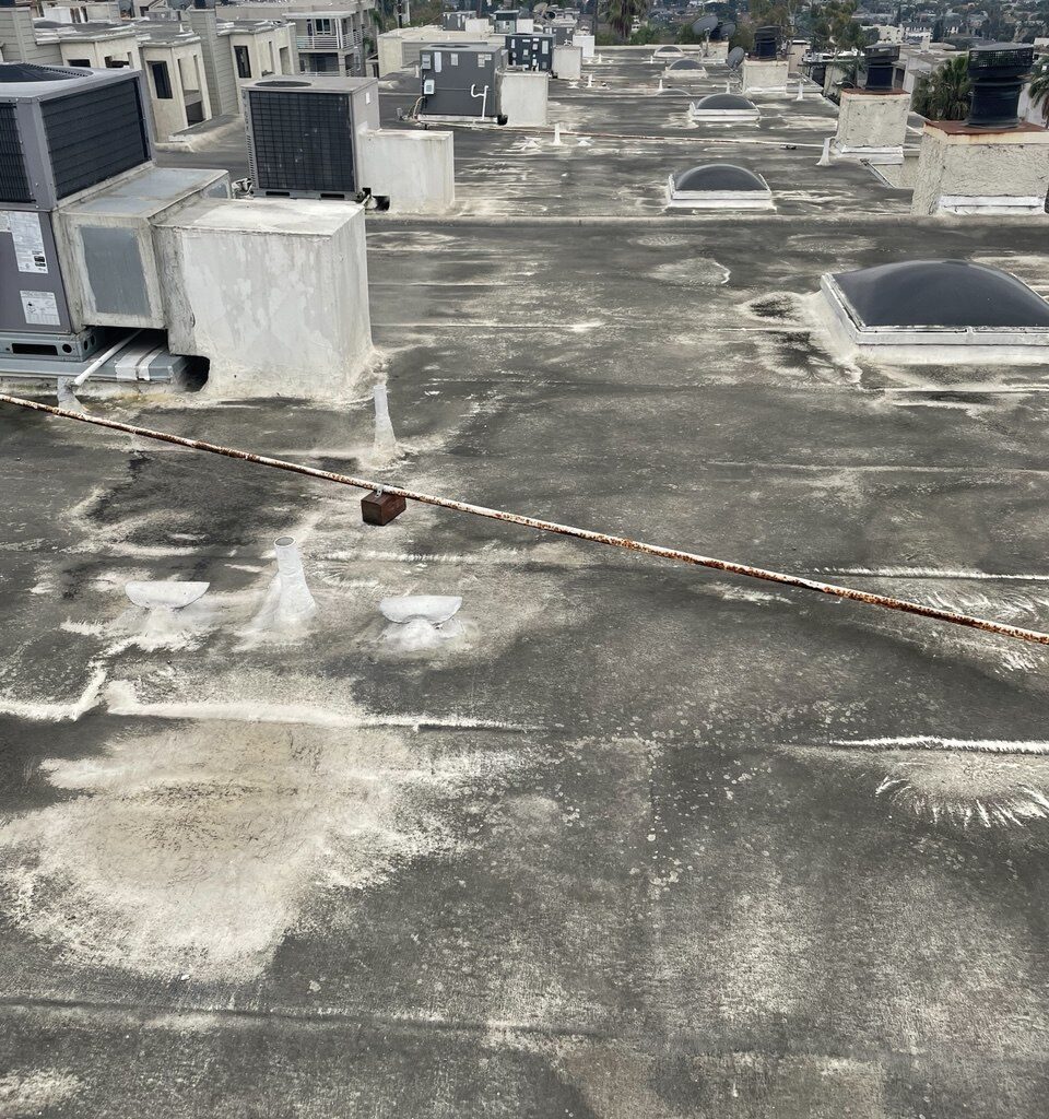 Weathered multi-family HOA flat roof surface in Signal Hill before silicone restoration.