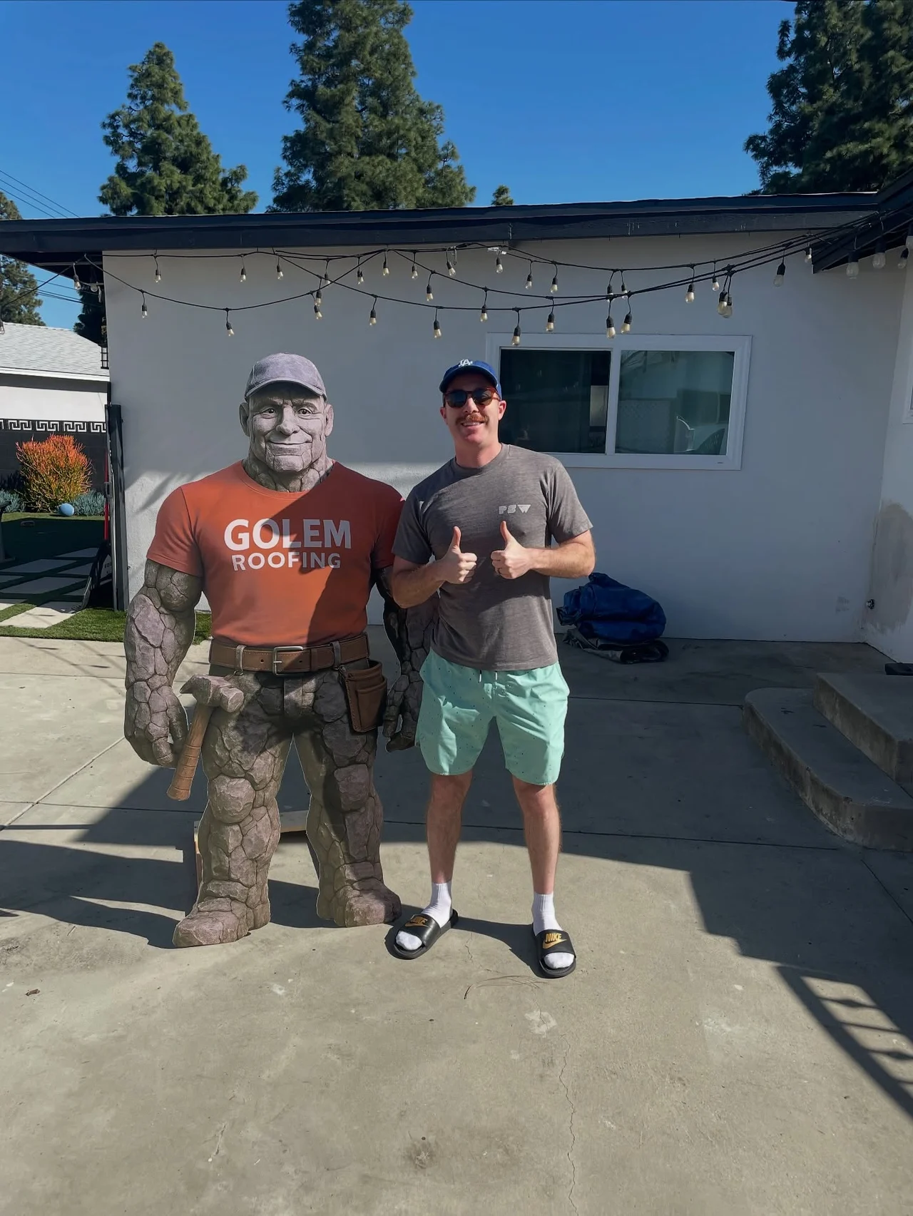 Golem Roofing team member with the company mascot outside a residential property