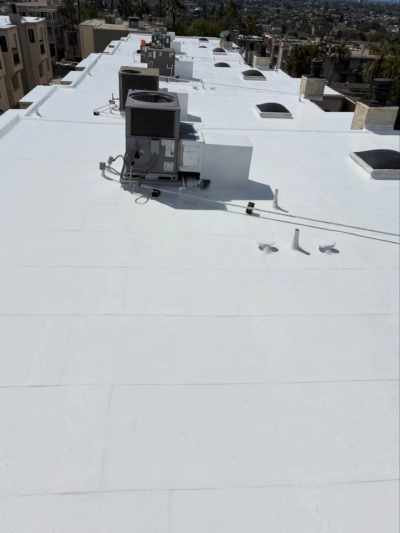 Close view of the finished white silicone roof coating around rooftop HVAC equipment