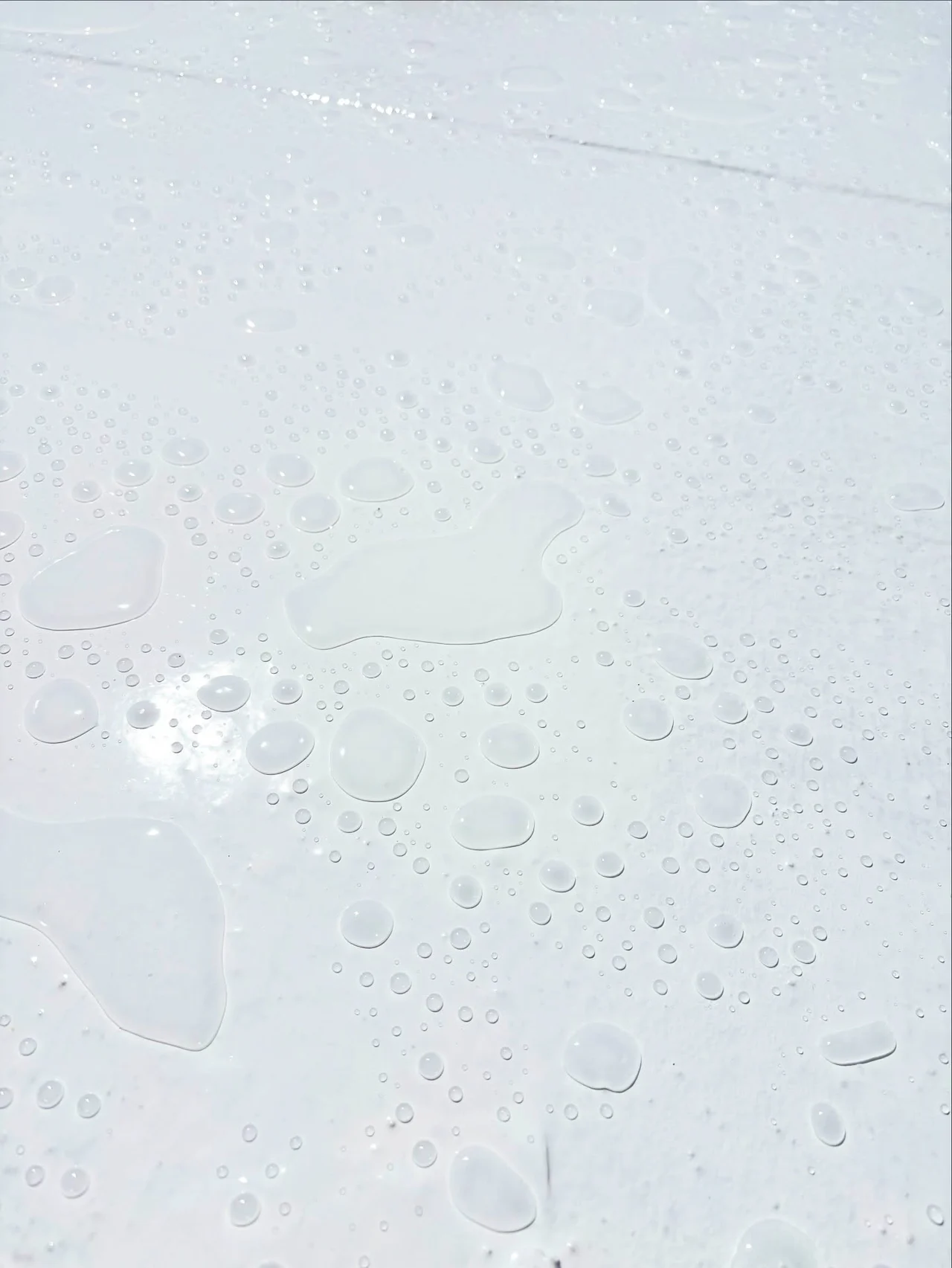 Water droplets beading on the white silicone-coated roof surface