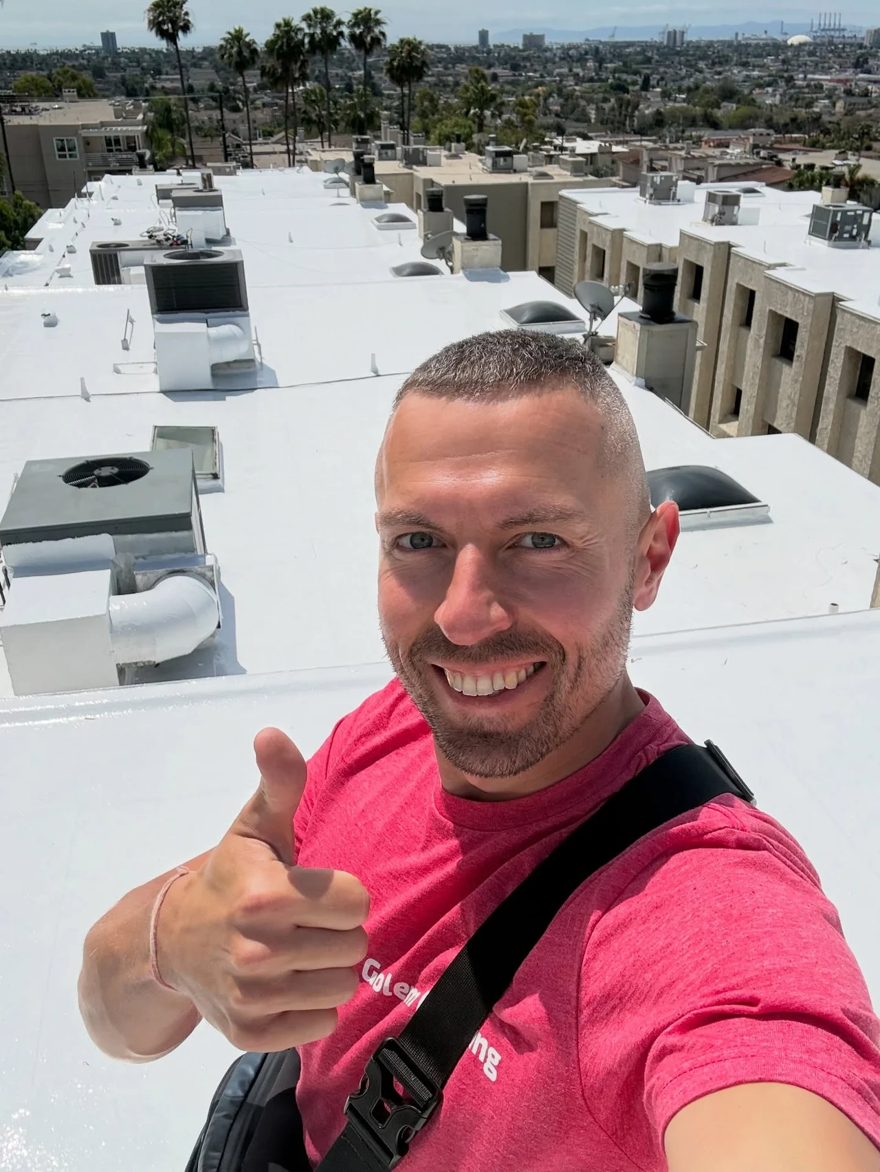 Golem Roofing team member giving a thumbs up on the completed white roof